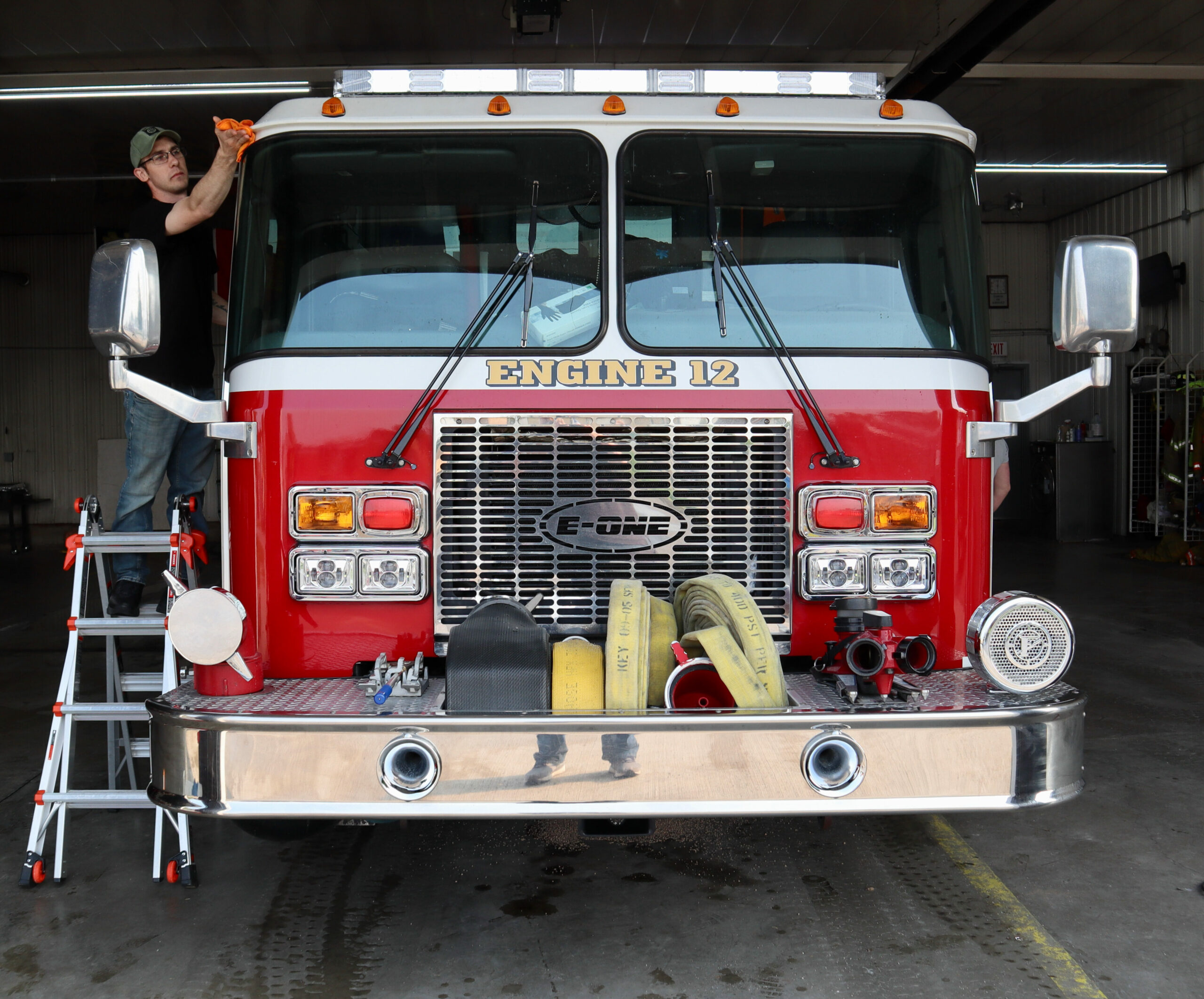 Austin Acker, a volunteer firefighter, cleans a fire truck in at the Ashley volunteer fire department firehouse in May 2023. Credit: James Bruggers 